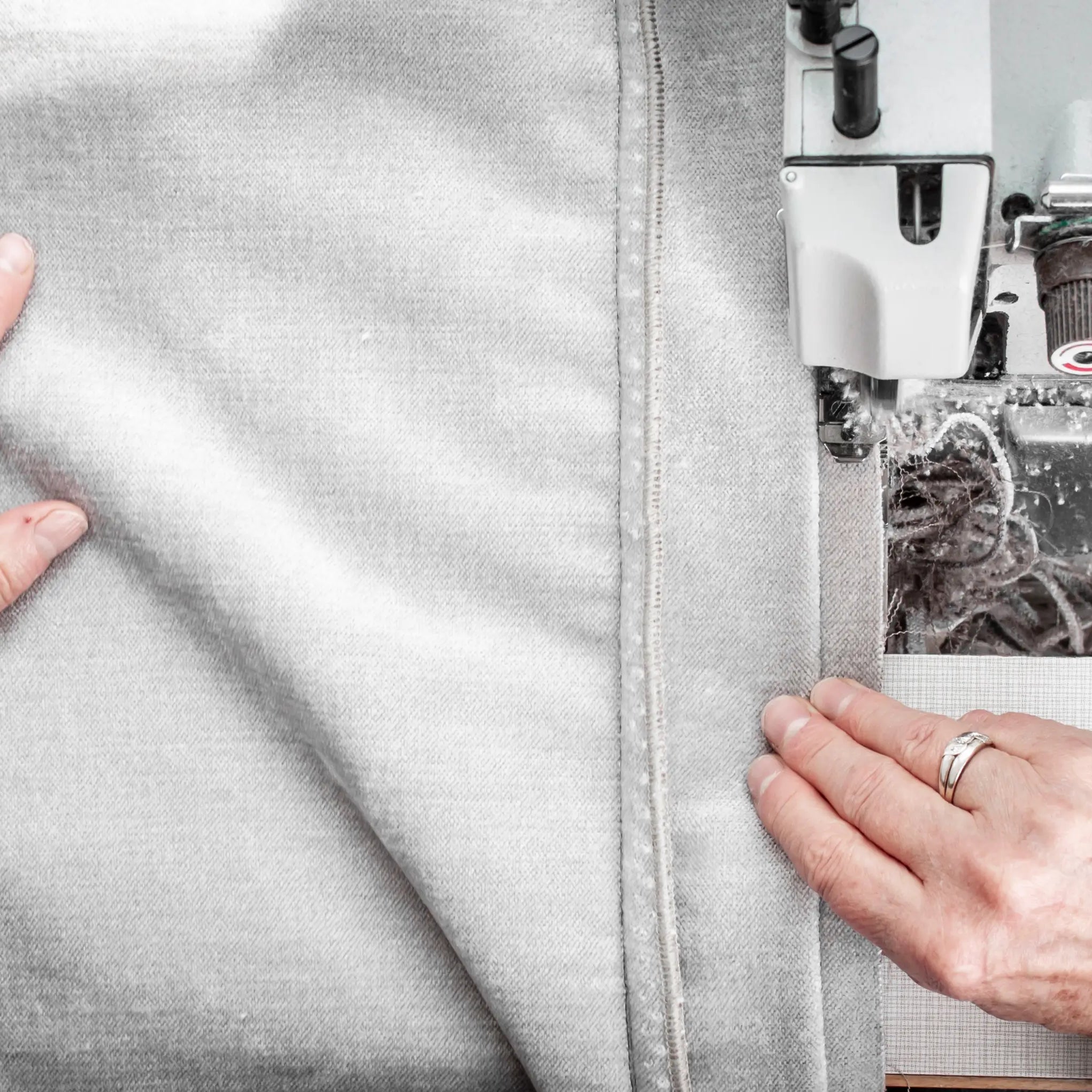Tailor working on a sewing machine with fabric, focusing on precise stitching