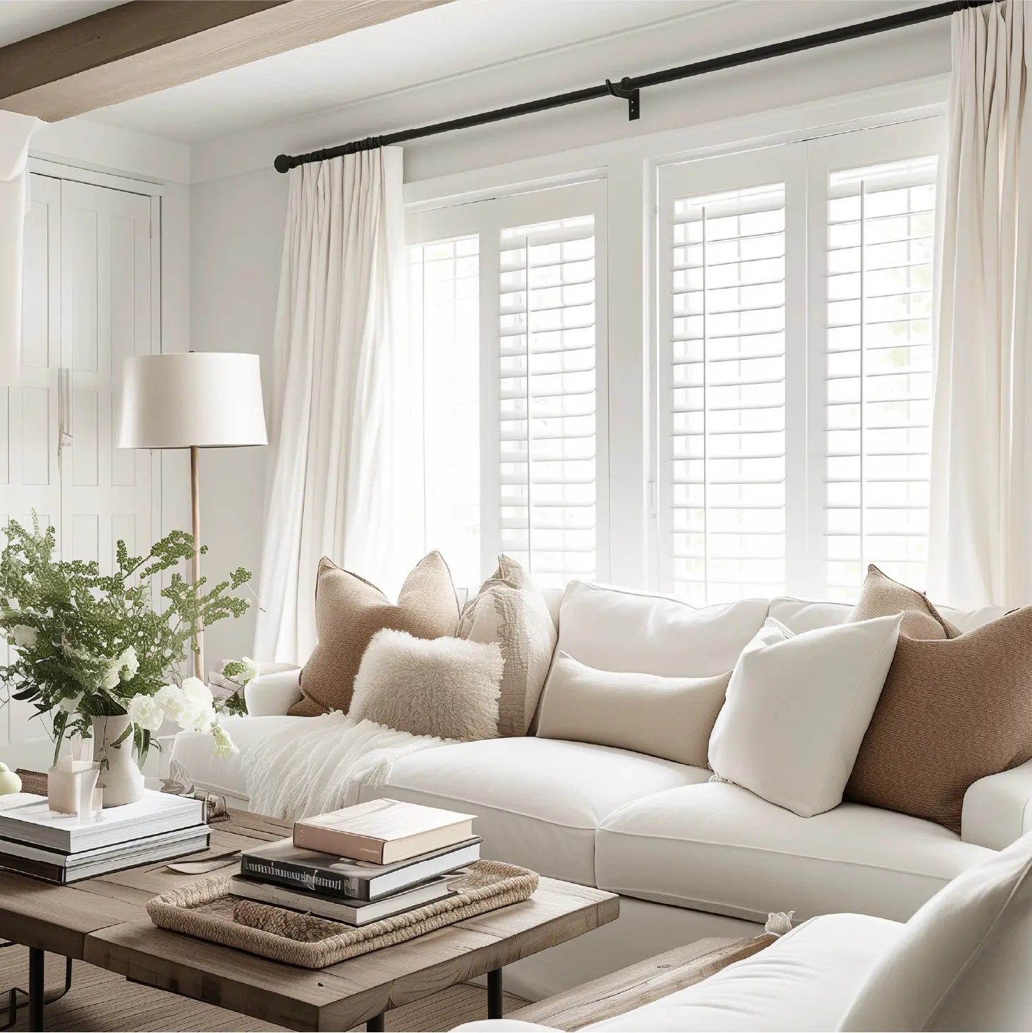 Living room with long white curtains, cozy sofa, wooden coffee table, and decorative pillows.