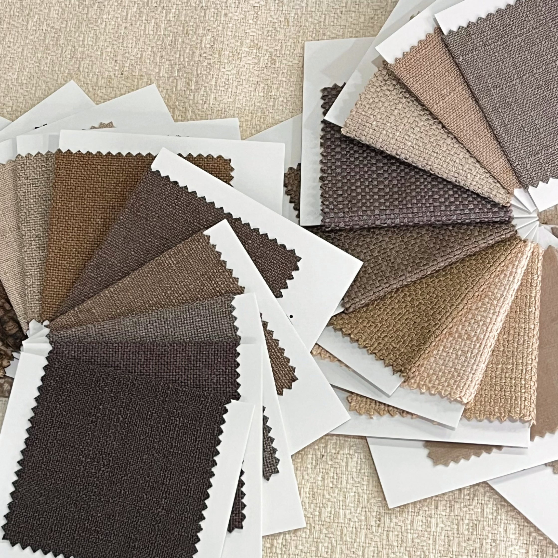 Free fabric sample selection in neutral color tones, offering various textures and shades for interior design and upholstery.