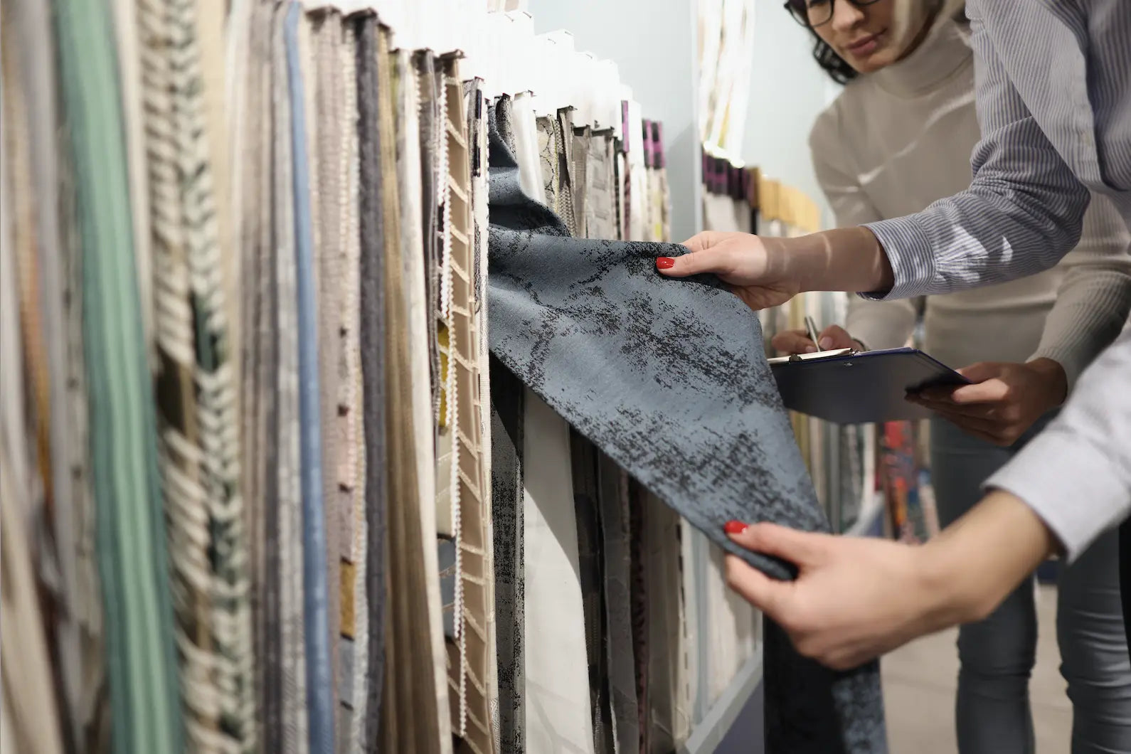 Customers browsing fabric selections, examining various textile options in a store.